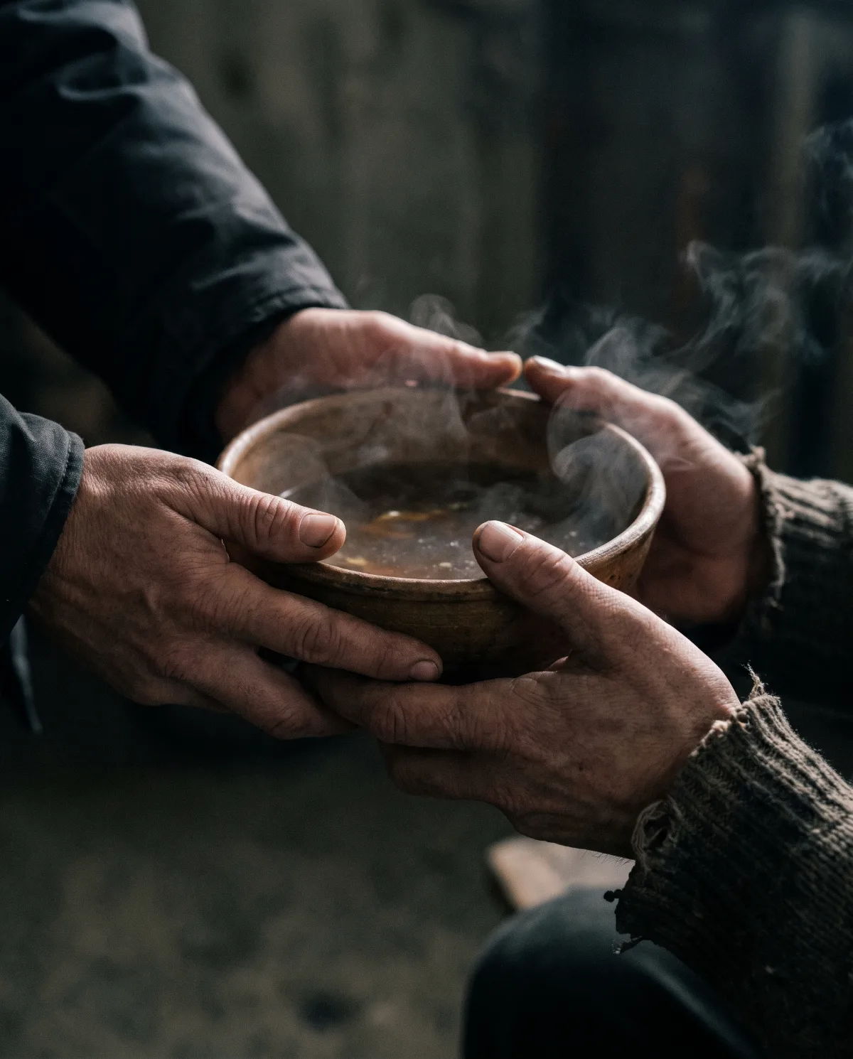 Mãos recebendo uma tigela de sopa em um abrigo (cena ilustrativa)